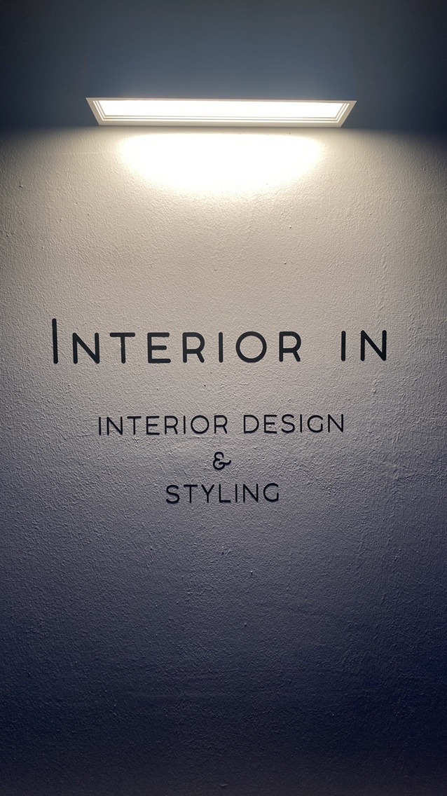 조명 아래 흰 벽에 붙은 Interior in 간판 글씨